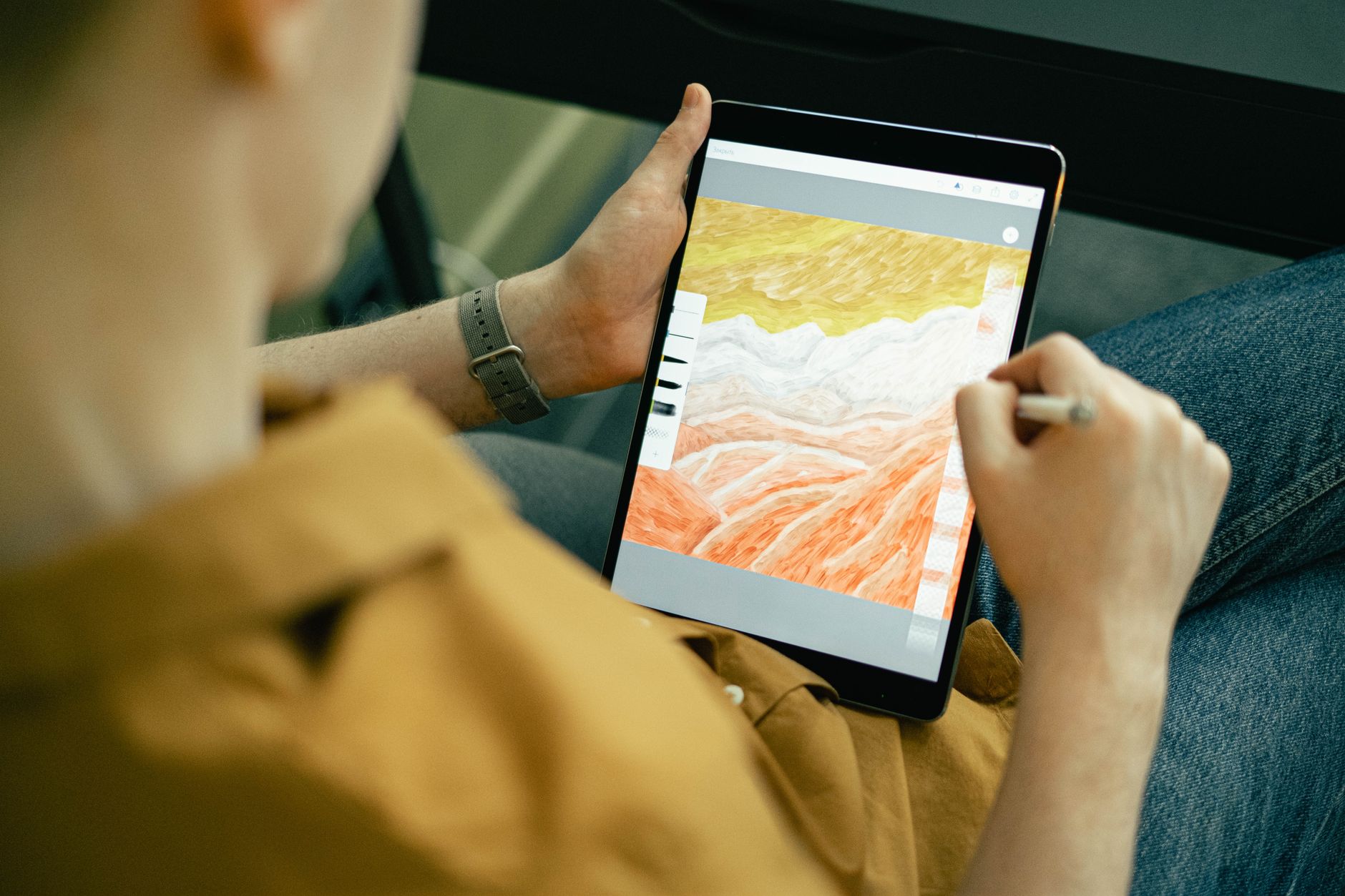 a designer working on digital art with a stylus and color swatches on a large monitor