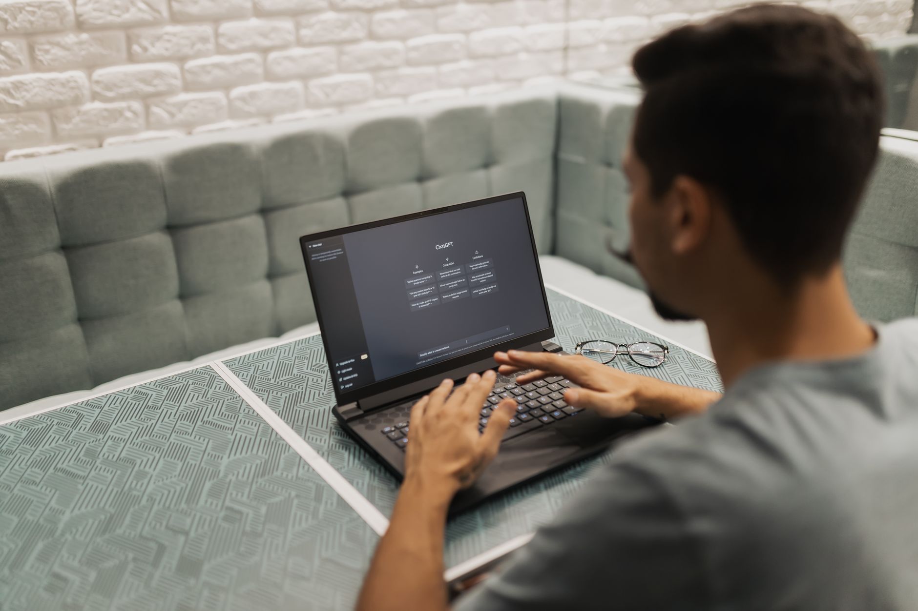 entrepreneur typing prompts into an AI assistant on a laptop