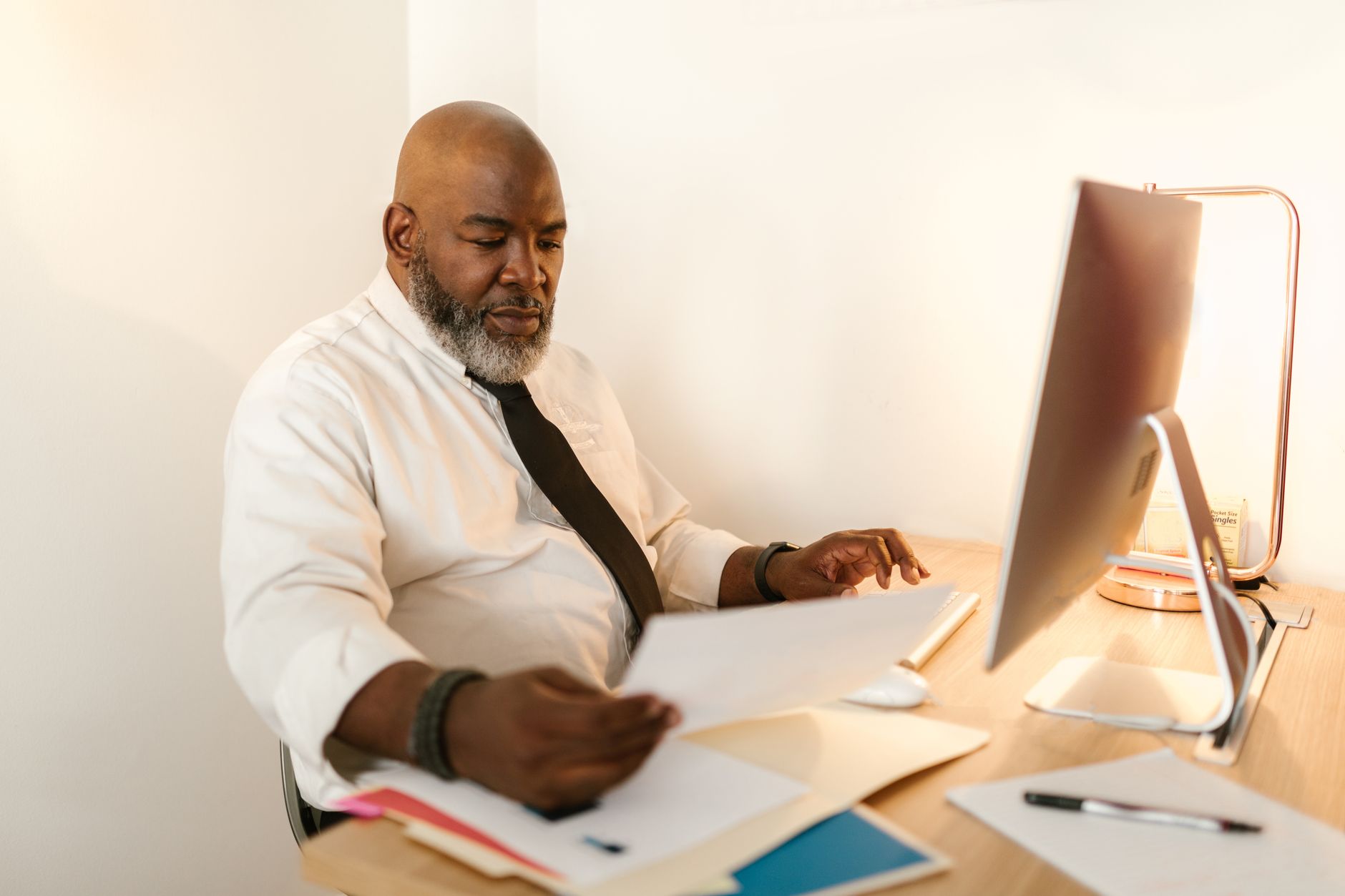 a journalist reviewing documents on a computer with a newsroom monitor in the background