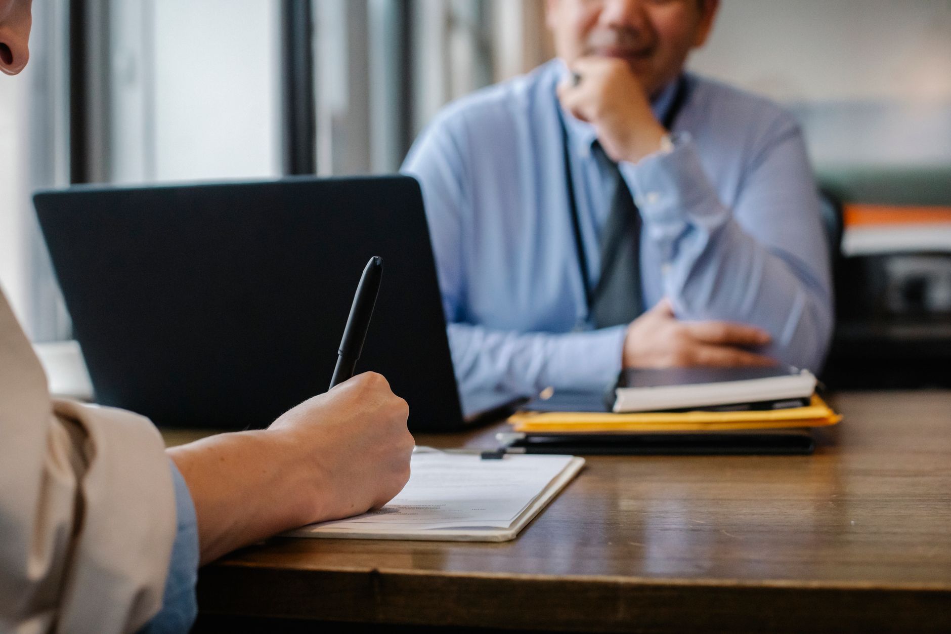 person editing a resume on a laptop next to a paper notebook