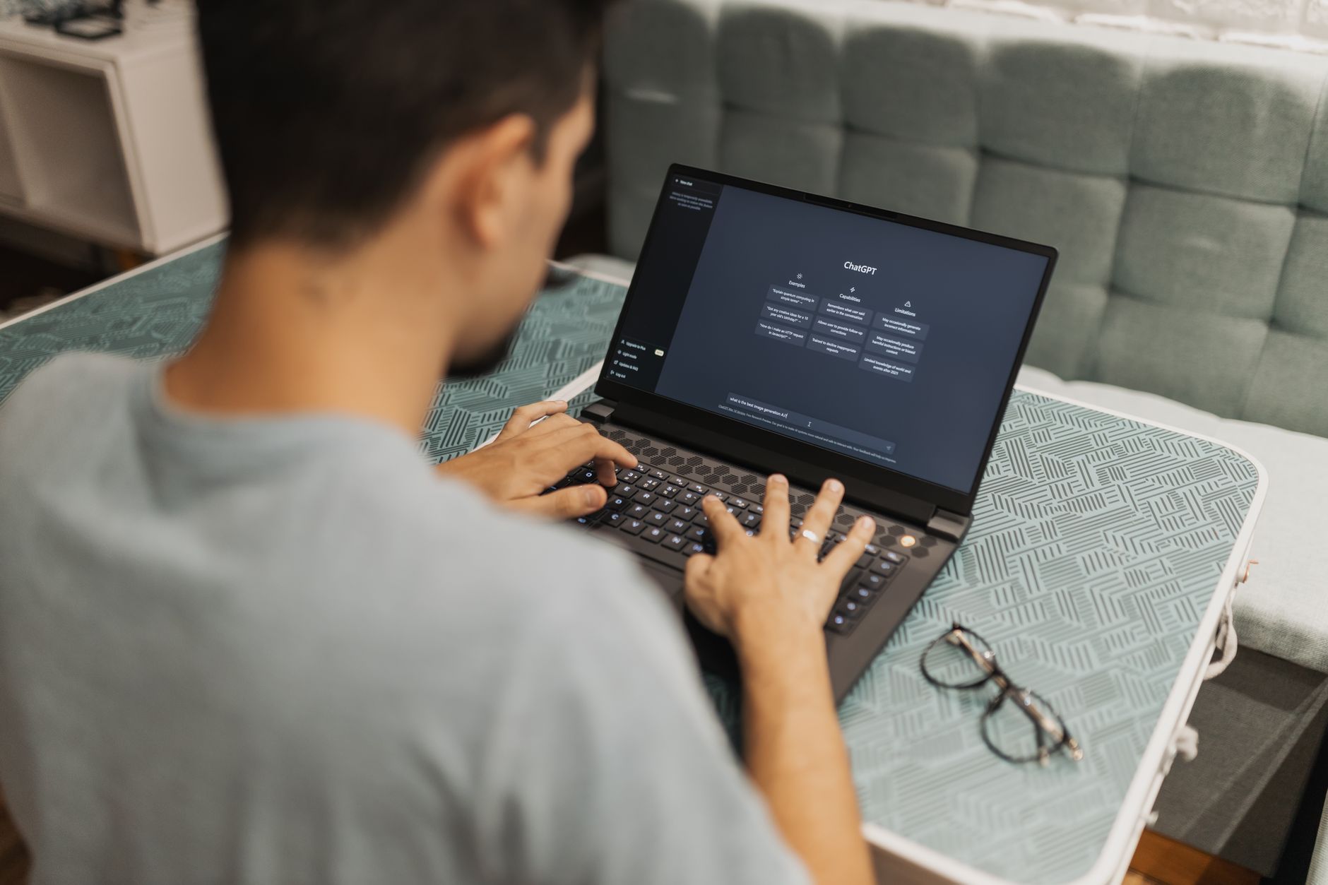 college student typing on laptop with ChatGPT interface visible