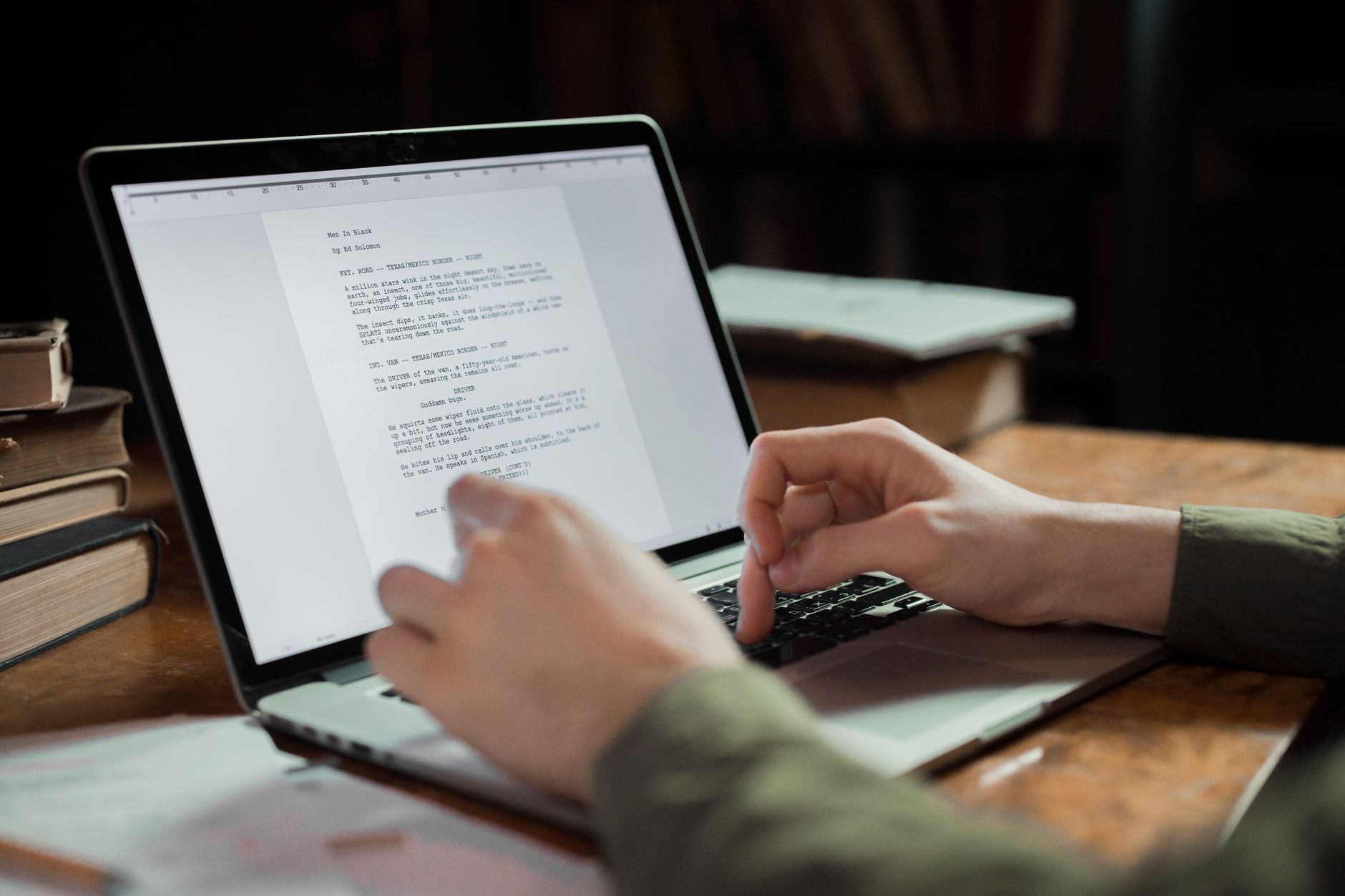 a writer editing text on a laptop with a notebook and coffee on the desk