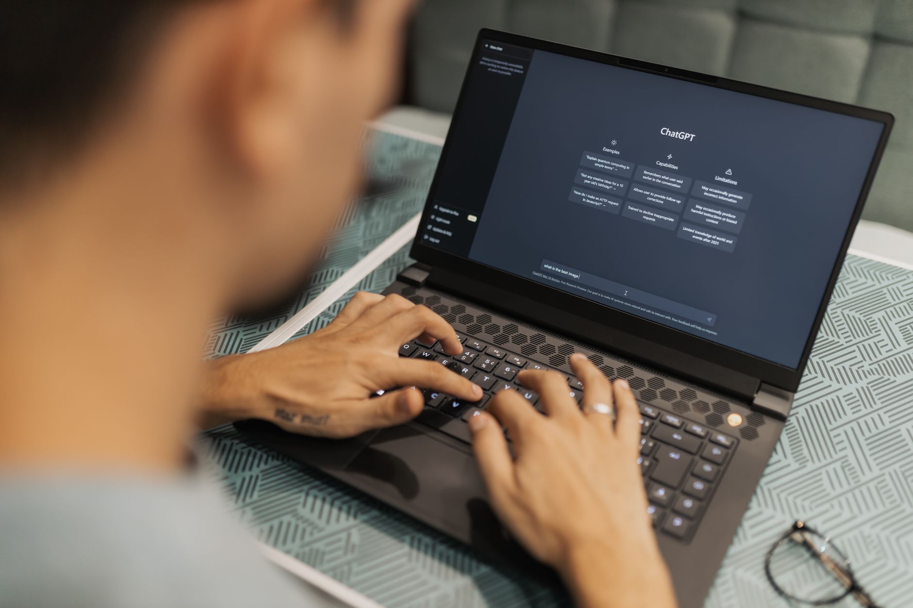 Person typing on a laptop showing an AI generated image gallery in a chat interface